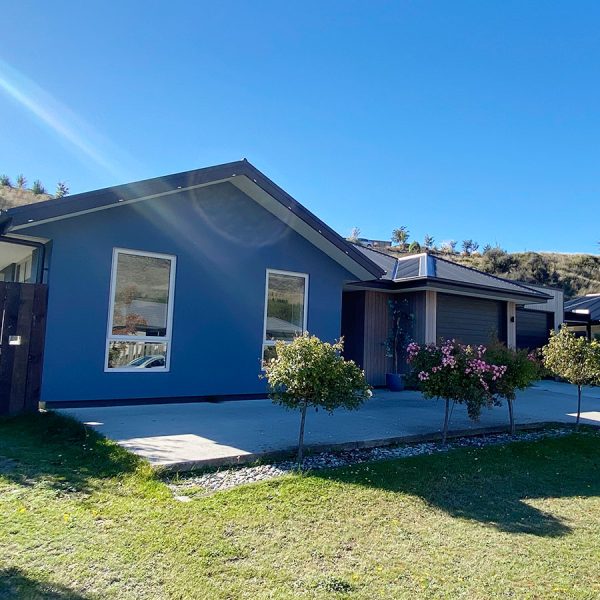 exterior freshly painted house in queenstown with shrubs in foreground and blue sky in background